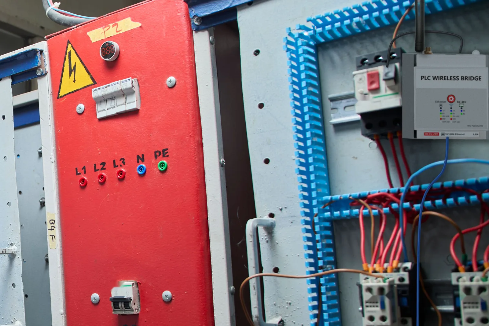 WS-PLCMU700 sur le rail DIN d'une armoire de commande, câble RS485 vers le PLC et câble réseau bleu vers un switch