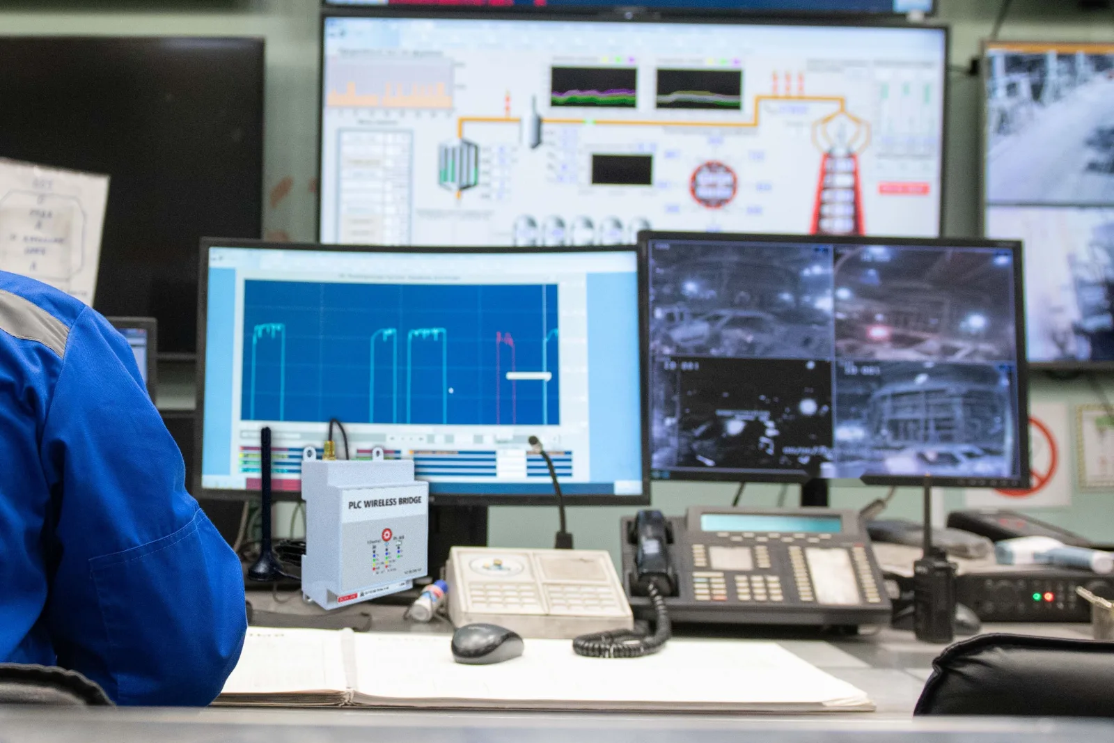 WS-PLCMU700 sur un pupitre de salle de contrôle, avec les vues SCADA et terrain sur les écrans à l'arrière