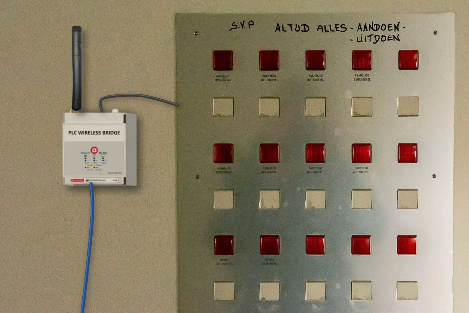 WS-PLCMU700 à côté du tableau de signalisation d'alarmes d'un local technique, câble de signal vers le tableau et câble réseau bleu passant en dessous