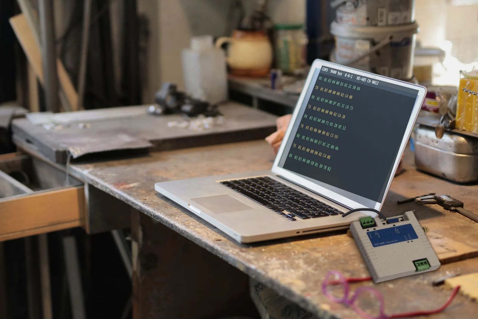 Ordinateur portable sur un établi affichant des données série, relié à un RD-485 par câble RS232