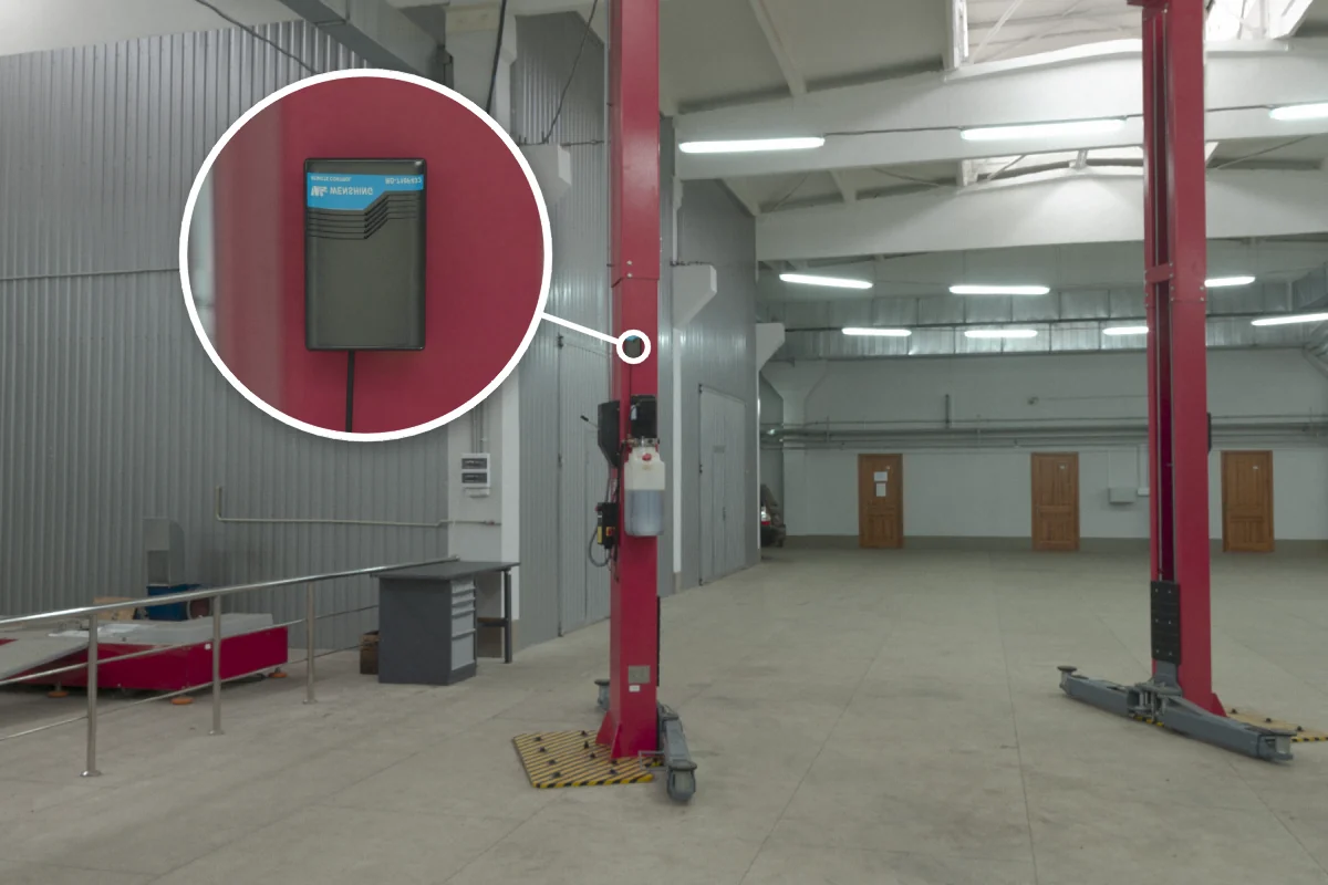 Two-post vehicle lift in a car service shop with RD-710F-433 rolling door remote controller on the column for remote up/down control